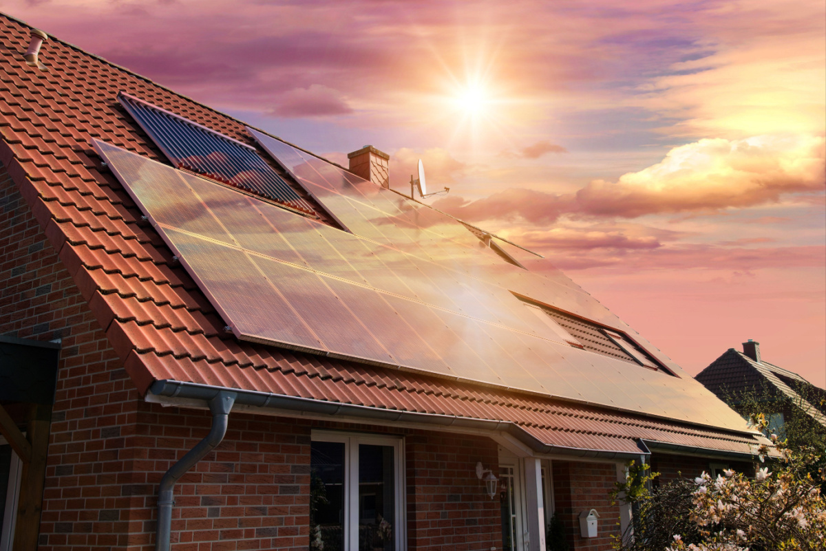 A house with the sun reflecting off of the solar panel on its roof.